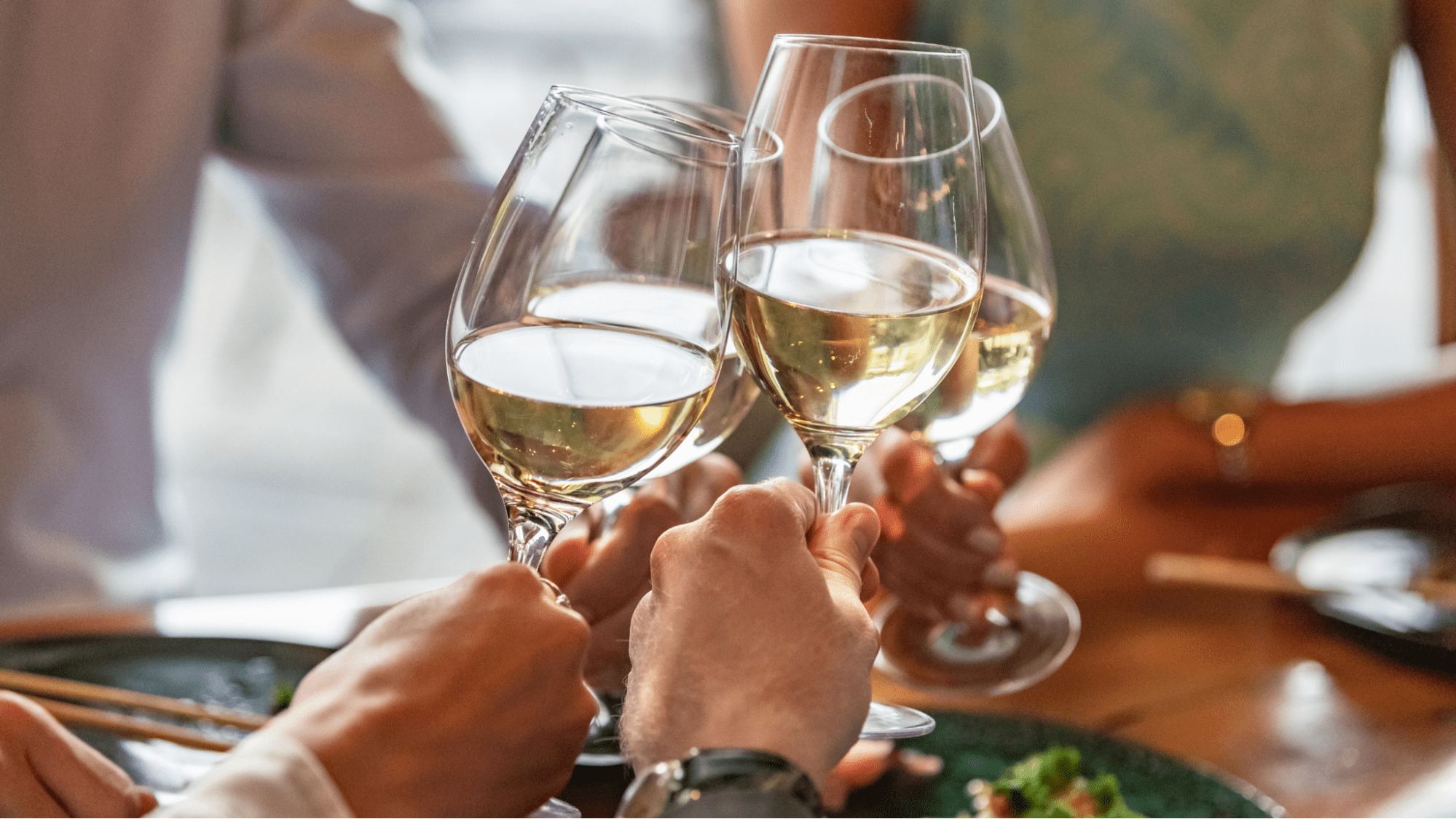 Friends cheersing white wine glasses